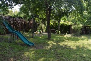 un parc avec une aire de jeux avec un toboggan et des arbres dans l'établissement La Métairie du Moulin de Meusnes, à Meusnes