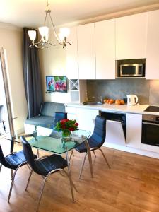 cocina con mesa de cristal y sillas en VILLA FLORANCE apartments with terraces & parking en Ventspils