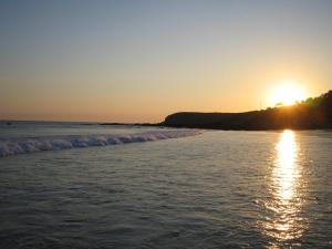 um pôr do sol na praia com o pôr do sol em Hotel La Costera em A Lanzada