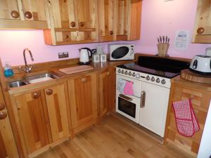 a kitchen with wooden cabinets and a white stove top oven at Seaside Apartment in Carbis Bay