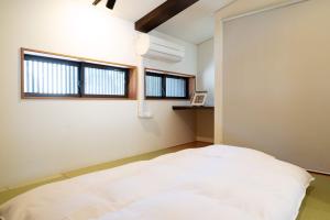 a bedroom with a white bed and two windows at Casaya TABI-NE in Kanazawa