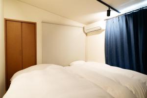 a bedroom with two white beds and a window at Casaya TABI-NE in Kanazawa