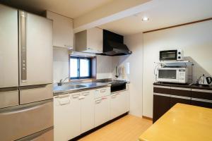 a kitchen with white cabinets and a sink and a microwave at Casaya TABI-NE in Kanazawa