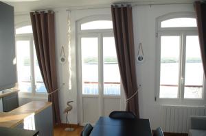 a living room with two windows and a table at Vue exceptionnelle sur la Baie de Somme in Saint-Valery-sur-Somme