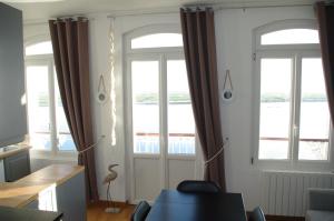 ein Wohnzimmer mit 2 Fenstern und einem Tisch in der Unterkunft Vue exceptionnelle sur la Baie de Somme in Saint-Valery-sur-Somme