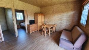 a room with a table and a couch and a bedroom at Agroturystyka Domki Eden in Sarbinowo