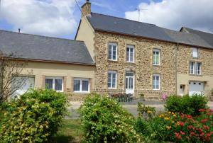 une ancienne maison en pierre avec des fleurs devant elle dans l'établissement Chambres " Orchidées ", à Saint-Denis-de-Gastines