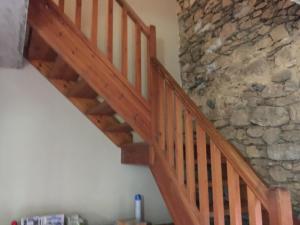 escalera de madera en una habitación con pared de piedra en Cal Pai en Pardines