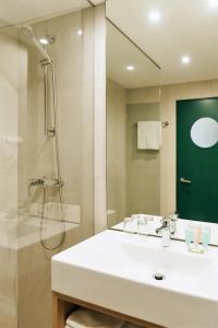 a bathroom with a sink and a shower and a mirror at Amazonia Lisboa Hotel in Lisbon