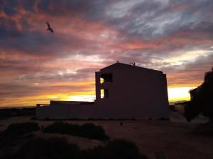 un bâtiment dans le désert avec un coucher de soleil en arrière-plan dans l'établissement Calatabarca B&B, à Tabarca