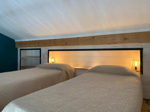 two beds in a bedroom with two lights on the wall at Belarra in Ciboure