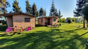 a house with a picnic table and chairs in the grass at Agroturystyka Domki Eden in Sarbinowo
