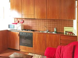 a kitchen with wooden cabinets and a stove and a microwave at Scoiattolo in Bardonecchia