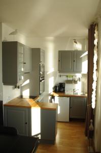 a kitchen with white cabinets and a wooden floor at Vue exceptionnelle sur la Baie de Somme in Saint-Valery-sur-Somme