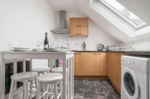 a kitchen with a bar with stools and a washer at Dunbar High Street One Bedroom Apartment in Dunbar