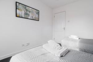 ein weißes Schlafzimmer mit einem Bett und einem Bild an der Wand in der Unterkunft Dunbar High Street One Bedroom Apartment in Dunbar