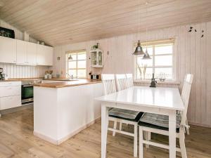 a white kitchen with a white table and chairs at 6 person holiday home in Blokhus in Blokhus