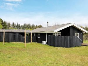 a black house with a fence in front of it at 6 person holiday home in Blokhus in Blokhus