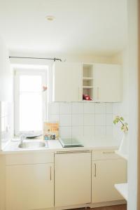 Una cocina con gabinetes blancos y un fregadero. en Landhaus Alger, en Immenstadt im Allgäu