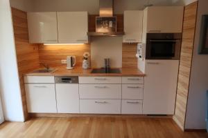 a kitchen with white cabinets and a wooden wall at Rose Garden Retreat Private Terrace Baden-Baden in Baden-Baden +12 photos
