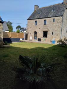 a large stone house with a palm tree in the yard at Les charmantes pierres percées in Ploumilliau