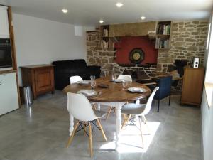 a dining room with a wooden table and chairs at Les charmantes pierres percées in Ploumilliau
