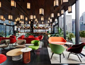 a living room filled with tables and chairs at citizenM New York Times Square in New York