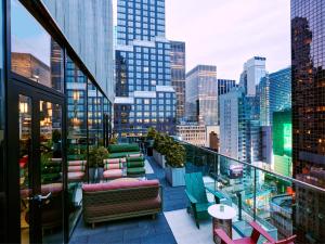 a balcony with chairs and tables and a city skyline at citizenM New York Times Square in New York