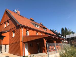 duży drewniany dom z czerwonym dachem w obiekcie Apartmány pod lanovkou w mieście Hořejší Vrchlabí