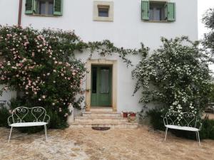 deux chaises assises devant une maison fleurie dans l'établissement B&B Giovannarolla Green House, à Ostuni