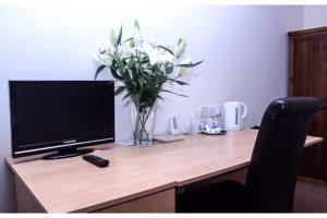 a desk with a computer monitor and a vase of flowers at Ashiana in Newark-on-Trent
