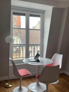 einem weißen Tisch mit einem Laptop vor einem Fenster in der Unterkunft Celect'In Lyon Suites climatisées SkyView in Lyon