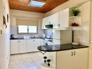 cocina con armarios blancos y encimera negra en Himonas Apartments en Pissouri