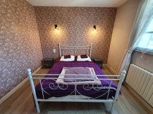 a bedroom with a bed with purple sheets and a window at LA MAISON DU MUGUET - Accueil Chevaux - Horse Friendly in Liart