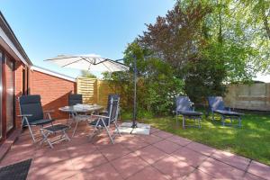 a patio with a table and chairs and an umbrella at Ferienhaus Klabautermann in Bensersiel +28 photos