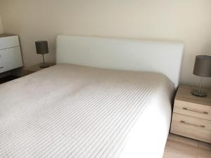 1 dormitorio con 1 cama blanca y 2 lámparas en Aqua Apartman Superior, en Velence