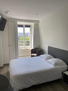 1 dormitorio con cama blanca y ventana en La Résidence de l'Orangerie en Estrasburgo