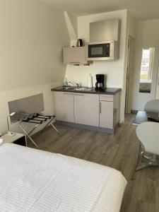 a room with a bed and a kitchen with a microwave at La Résidence de l'Orangerie in Strasbourg