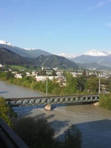 un puente sobre un río con montañas en el fondo en Close en Innsbruck