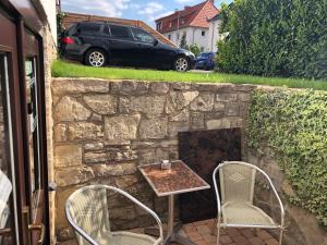 a stone wall with two chairs and a table and chairs at Pension zum Ringelberg in Erfurt