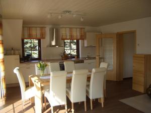 a kitchen and dining room with a wooden table and white chairs at Ferienwohnungen Schulze Oppach Oberlausitz - 5 Sterne in Oppach