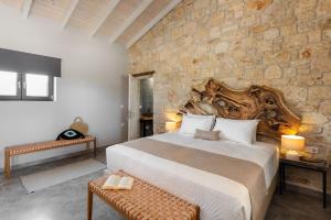a bedroom with a large bed and a stone wall at "Four Olives" Luxury Rooms, Afitos #FeelsLikeHome in Afitos