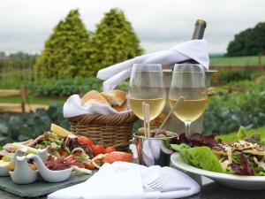 a table with two glasses of white wine and food at The Holcombe in Holcombe