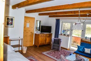 a living room with a bed and a tv and a window at Gasthof Pension Lanzenhof in Going am Wilden Kaiser