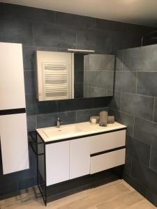 a bathroom with a white sink and black tiles at Villa patio terrasse privative océan 10 min a pied in Seignosse