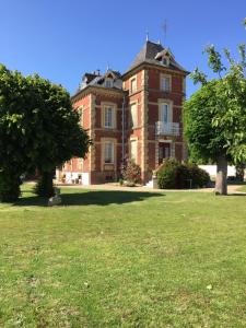 an old brick building with trees in a field at maison de maitre in Fleury-sur-Andelle