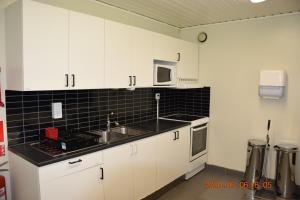 a kitchen with white cabinets and a sink and a microwave at Kapellskärs camping in Gräddö