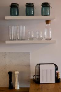 a shelf with glasses and a toaster on a table at Apartament Gdańsk Baltica Towers 7floor in Gdańsk