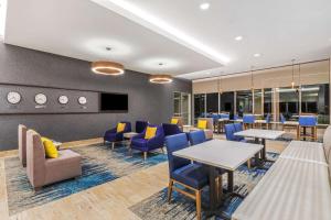 a waiting room with tables and chairs and aktopphrinephrinephrinephrinephrinephrine at La Quinta Inn & Suites by Wyndham Kansas City Beacon Hill in Kansas City