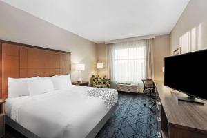 a hotel room with a bed and a flat screen tv at La Quinta Inn & Suites by Wyndham Kansas City Beacon Hill in Kansas City
